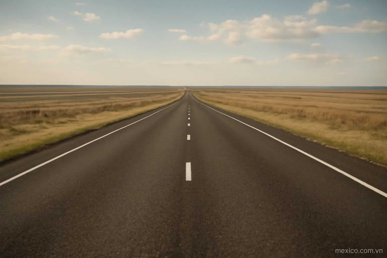 A long straight highway crossing open terrain toward the horizon, wide view, no text