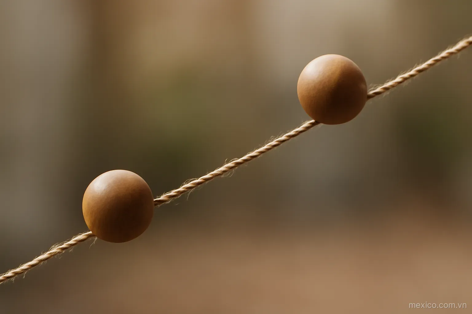 Two beads resting at different heights on the same sloped string, side view, no text