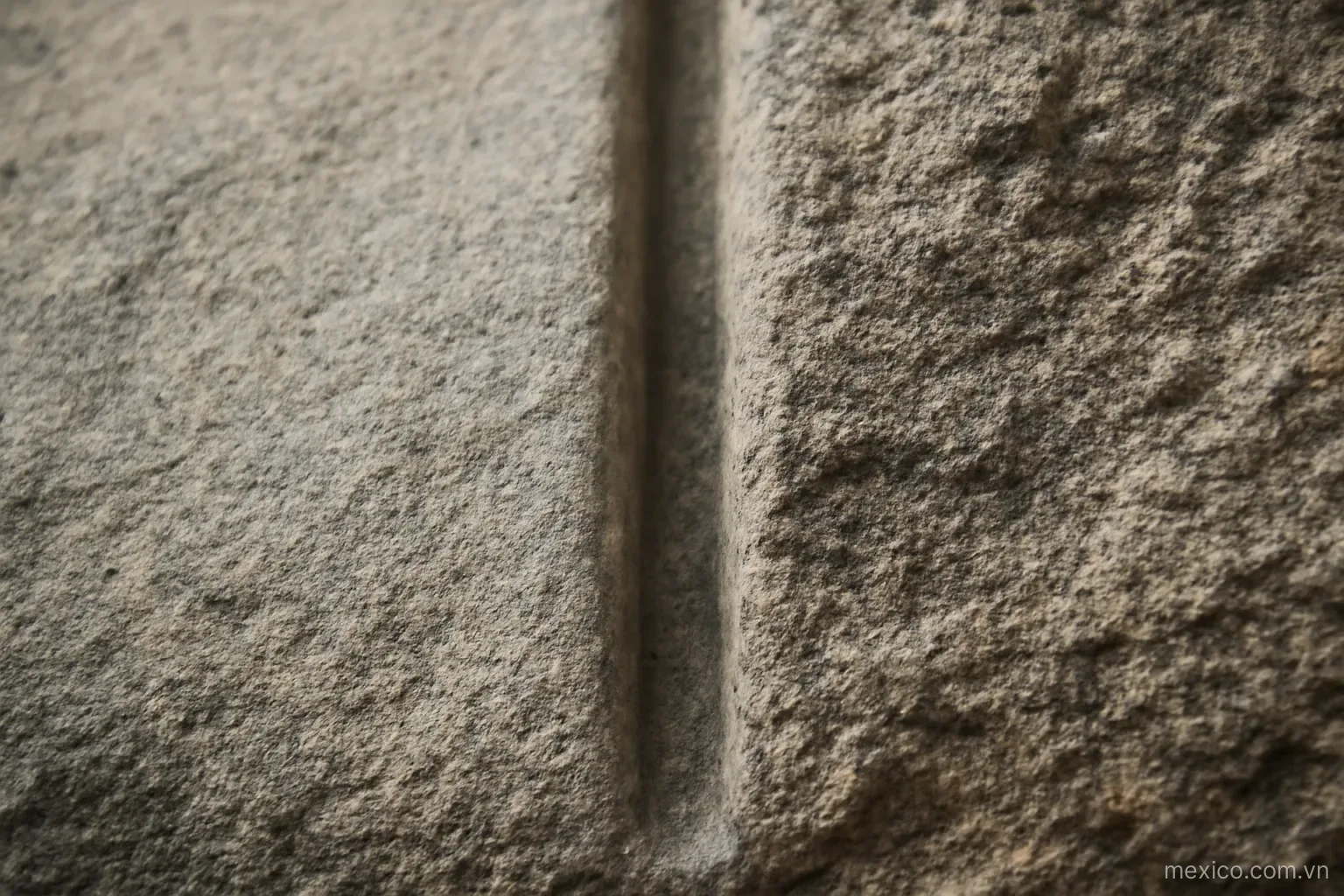 A straight groove in stone with one side worn smooth and the other side left rough, close view, no text