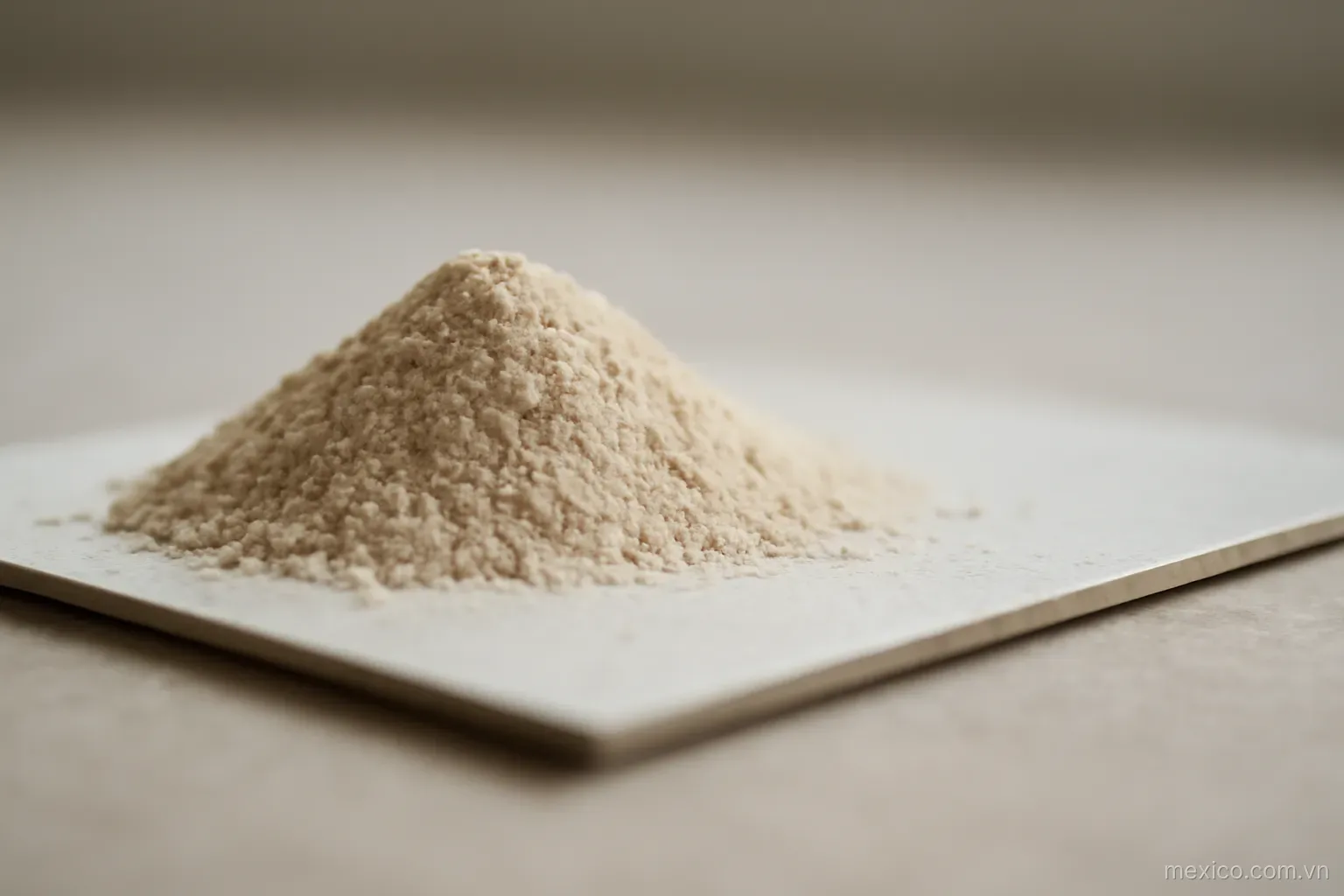 Powder gathered thickly at one edge of a thin plate and thinning toward the other, side view, no text
