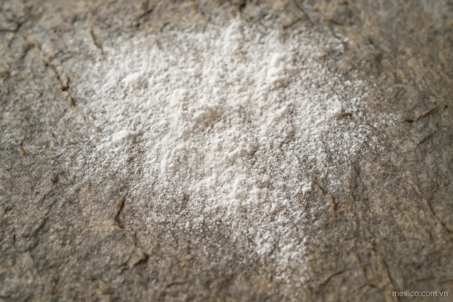 Powder settling into the natural grooves of a rough stone slab, overhead view, no text