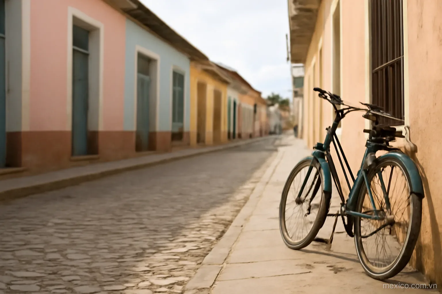 A pastel colonial street with low houses and a bicycle leaning on a wall, eye level, no text