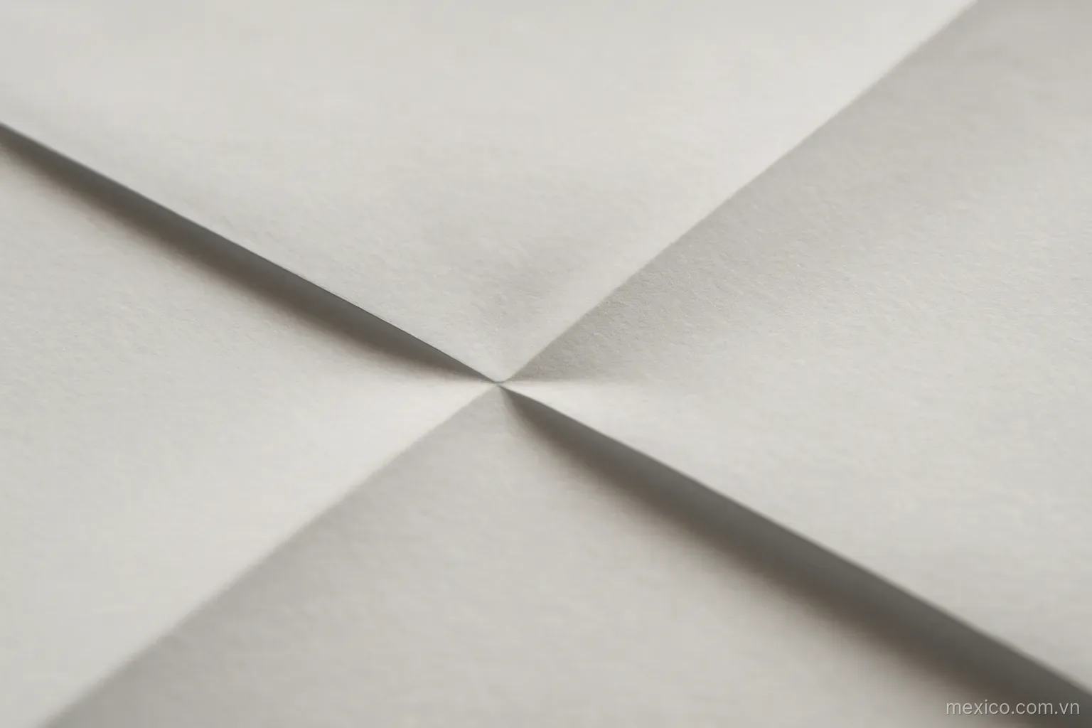 A point where two sets of paper creases intersect at a sharp angle, close overhead view, no text